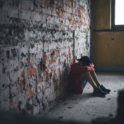 Sad and disappointed teenagers boy sitting on chair indoors in abandoned building.